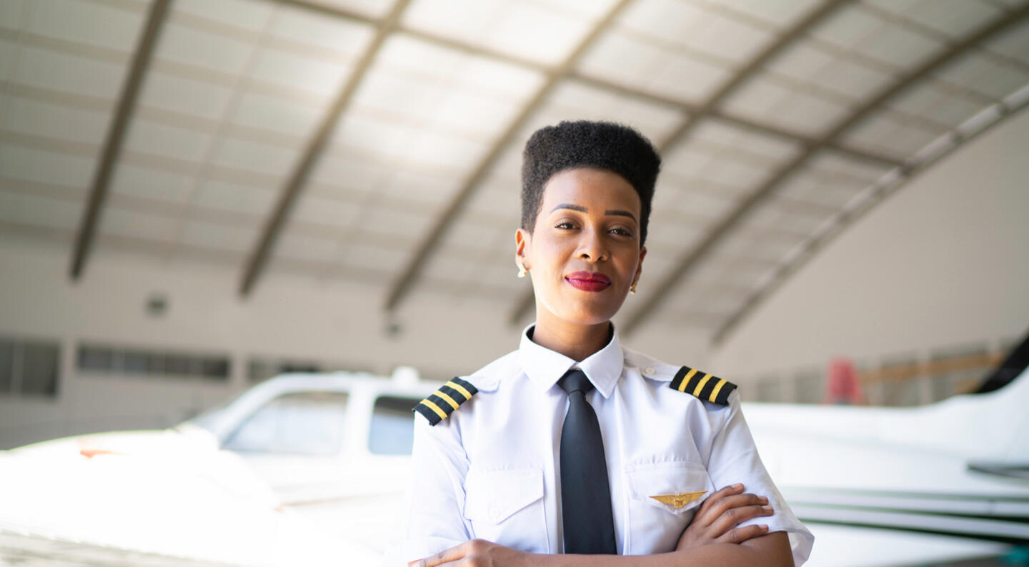 Portrait of airplane pilot in a hangar and looking at camera